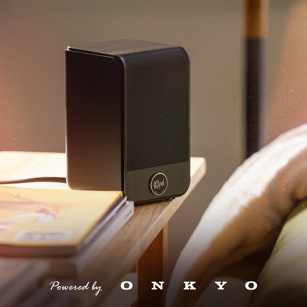 Klipsch Flexus Surrounds NA Black Klipsch Flexus Surr 100 on side table beside couch with PBO logo