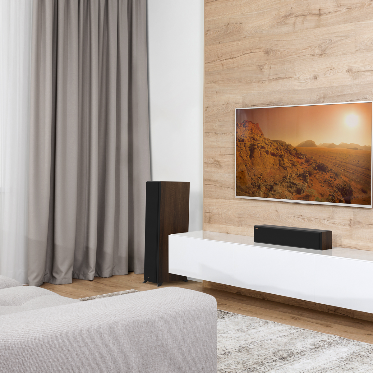 Klipsch RP-404C II Ebony RP 404C II sitting on a white credenza under a TV with its grille on